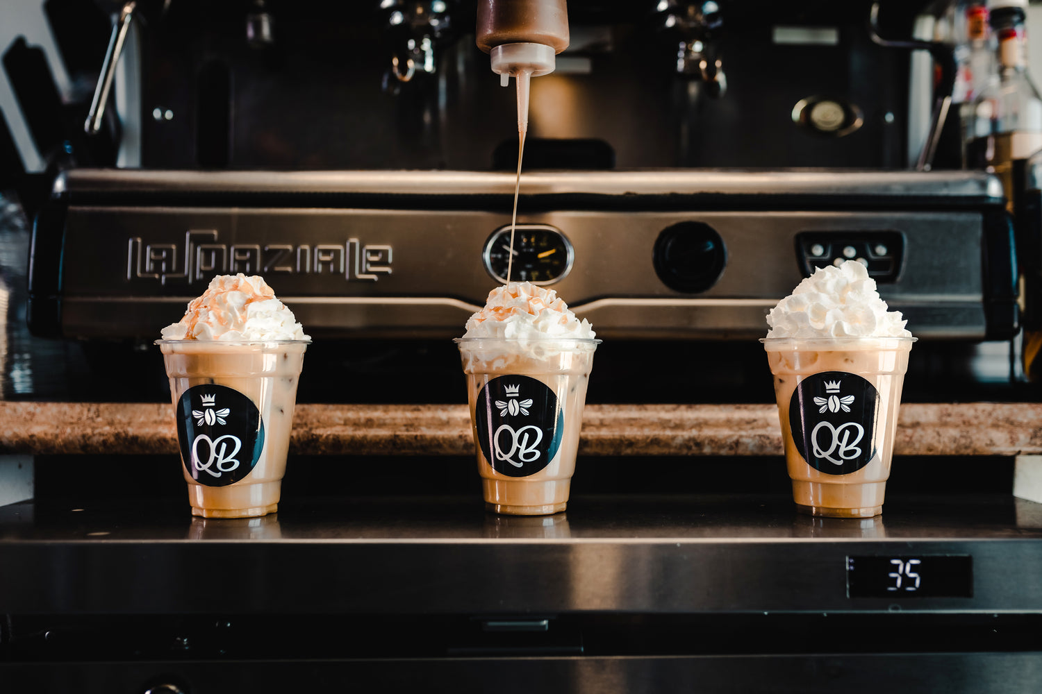 three coffee drinks atop a counter with an espresso machine in the background